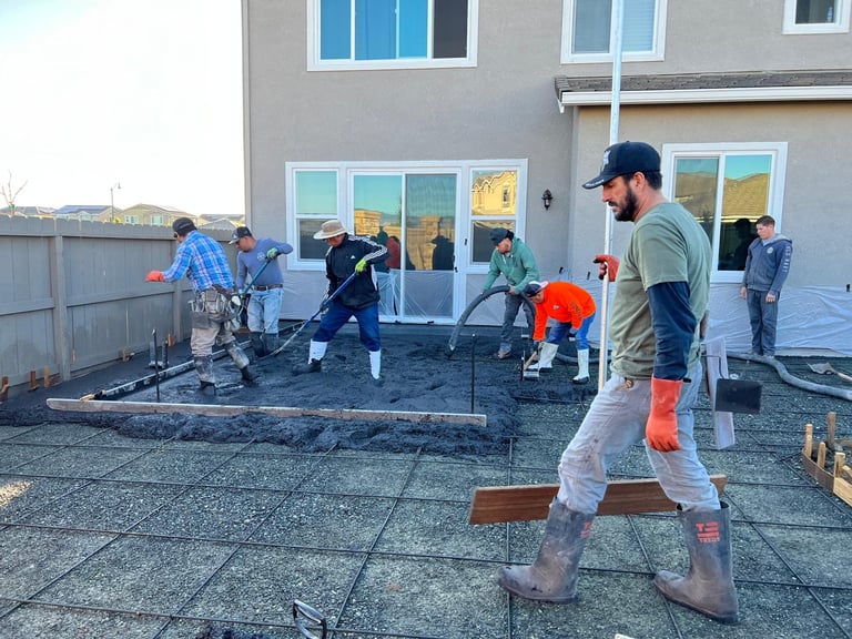 Workers installing or repairing roof materials on a residential building with multiple people in hard hats working on the rooftop